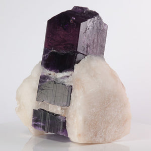 Scapolite Mineral sample with purple and gray crystal structure on a white background