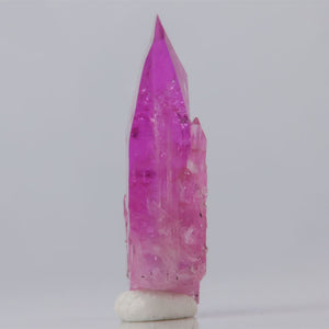 Pink Tanzanite crystal on a white base against a light gray background