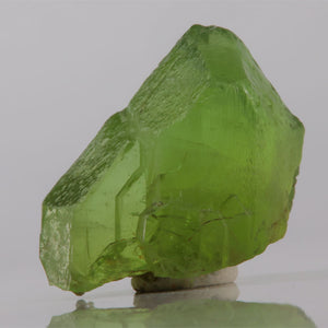 Green crystal on a reflective surface with a gray background