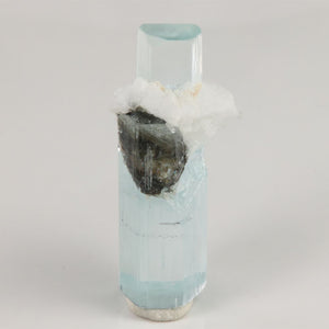 Front view of 7.02 gram aquamarine showing its light blue color, transparent hexagonal faces, and contrasting dark mineral.