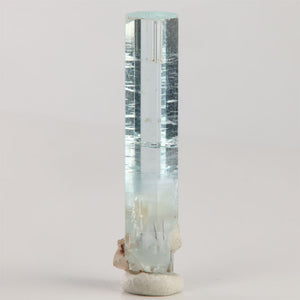 Front view of 3.54 gram aquamarine showing a distinct horizontal growth line and attached white mineral matrix near the base.