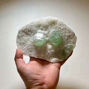 Pale green fluorite specimen with sparkling crystal background
