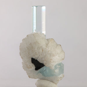 Side view of Pakistani aquamarine specimen showing a clear hexagonal termination and white crystals surrounding its base.