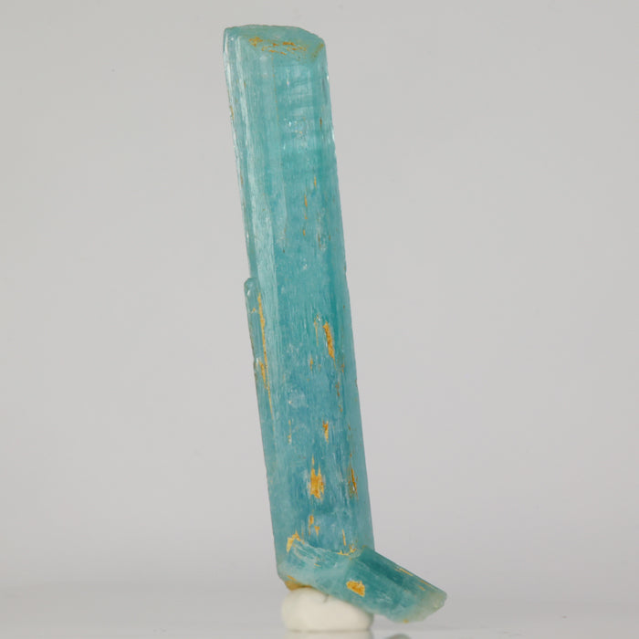 Aquamarine crystal with gold inclusions on a white background