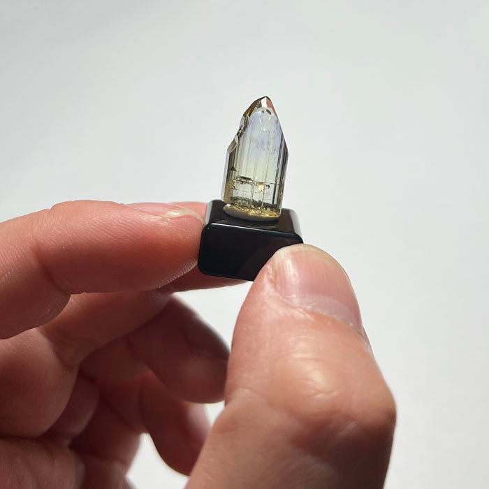 Hand holding a yellow tanzanite crystal