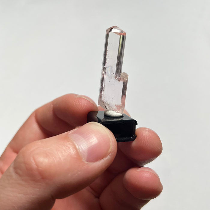 Clear topaz crystal with pink accents on a light gray background