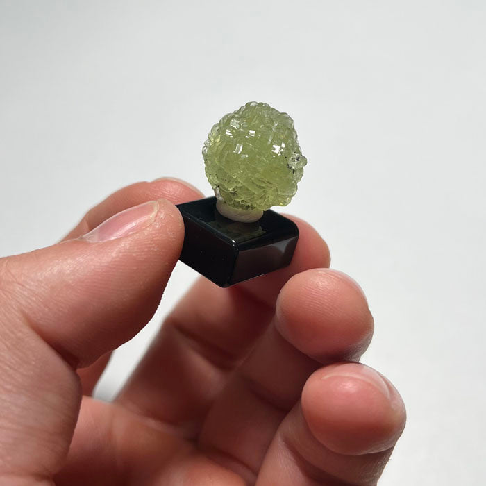 Green prehnite crystal on a white base with a light gray background