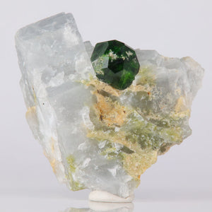 Mineral sample with a green demnatoid garnet crystal on a white background