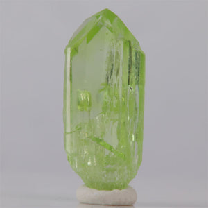 Green crystal on a white base against a gray background