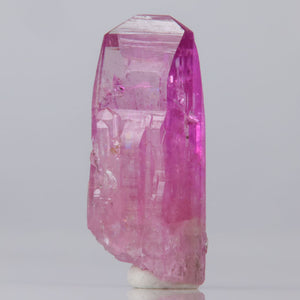 Vivid Pink Natural Tanzanite crystal on a gray background