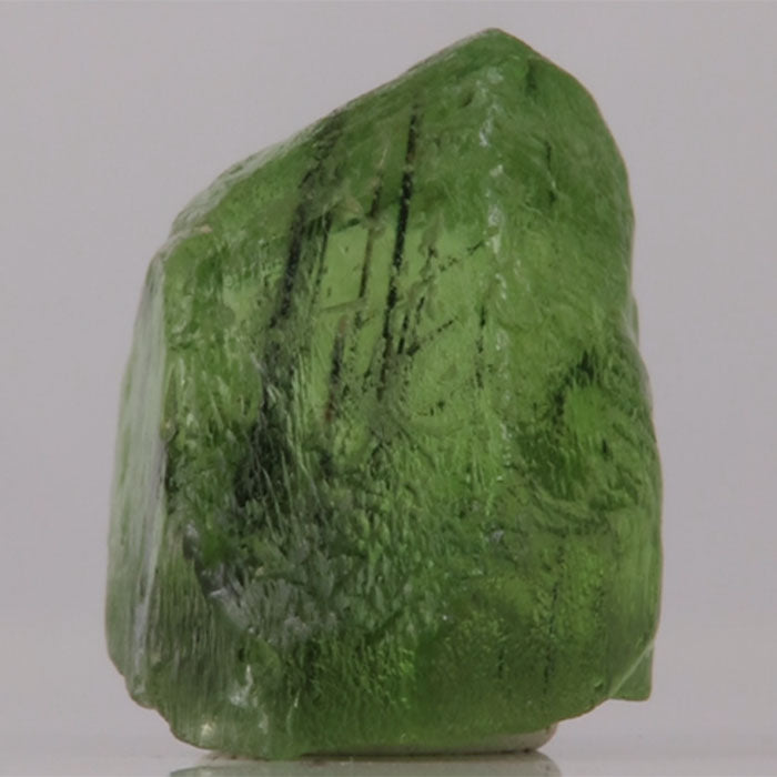 Green Peridot crystal rock on a gray background