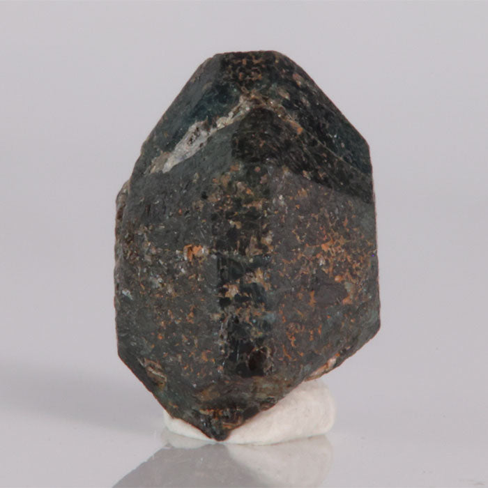 Alexandrite Mineral sample on a white stand against a gray background
