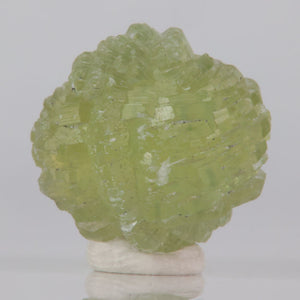 Gemmy Green crystal on a white base against a light gray background