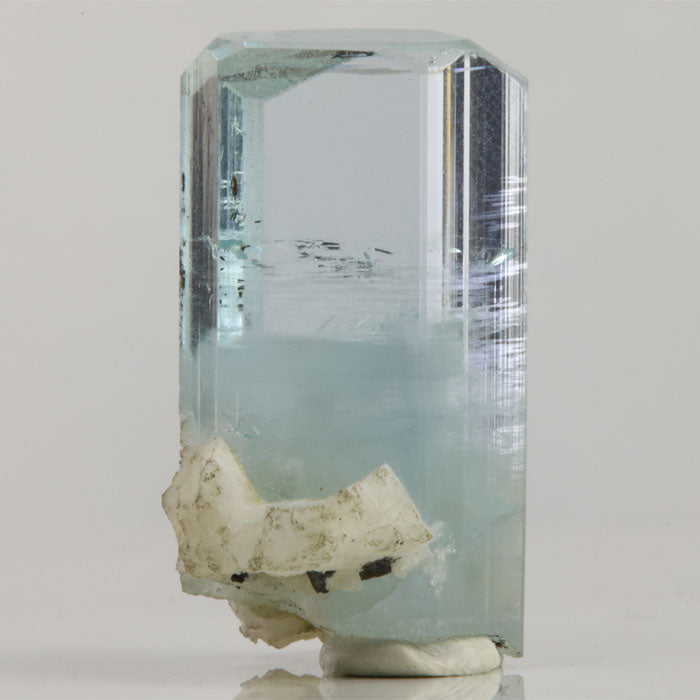 Side view of Pakistani aquamarine revealing internal growth patterns, scattered dark inclusions, and reflective crystal faces.
