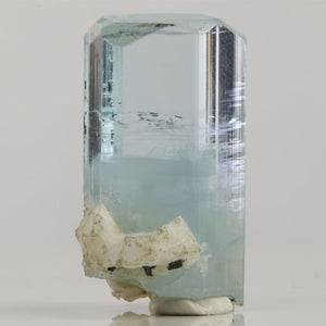 Side view of Pakistani aquamarine revealing internal growth patterns, scattered dark inclusions, and reflective crystal faces.