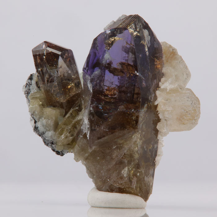 Mineral specimen with purple and brown crystals on a white background