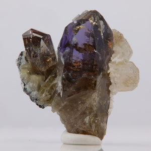 Mineral specimen with purple and brown crystals on a white background