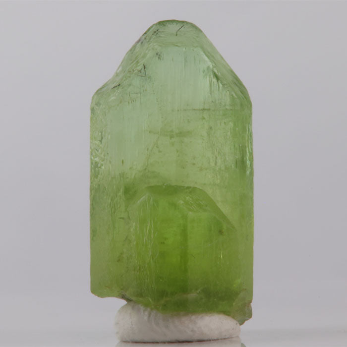 Green crystal on a white base against a gray background