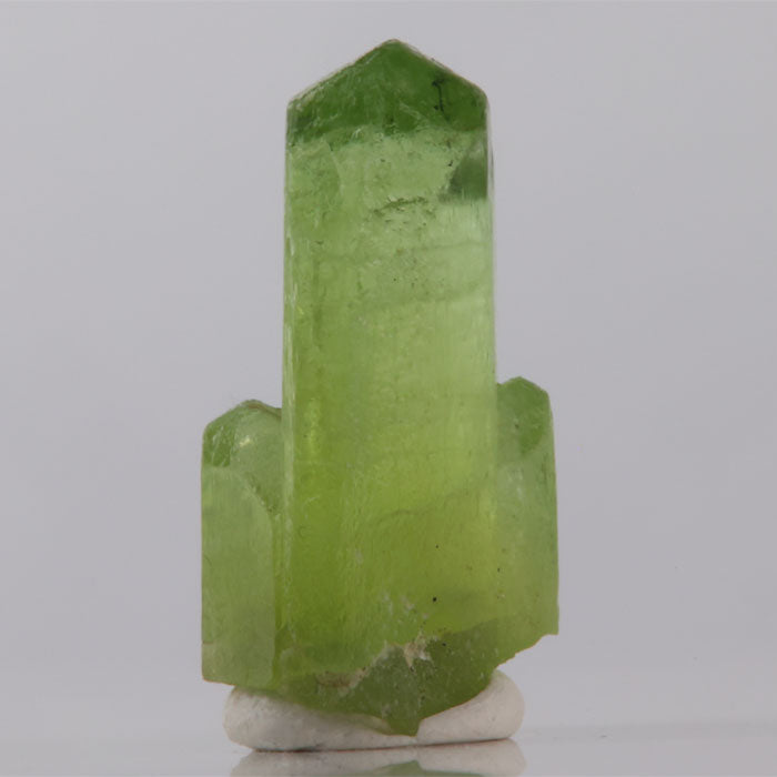 Green crystal on a white base with a gray background