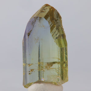 Clear tanzanite crystal with yellow and purple inclusions on a white background