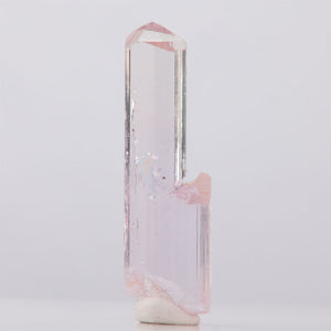 Clear topaz crystal with pink accents on a light gray background