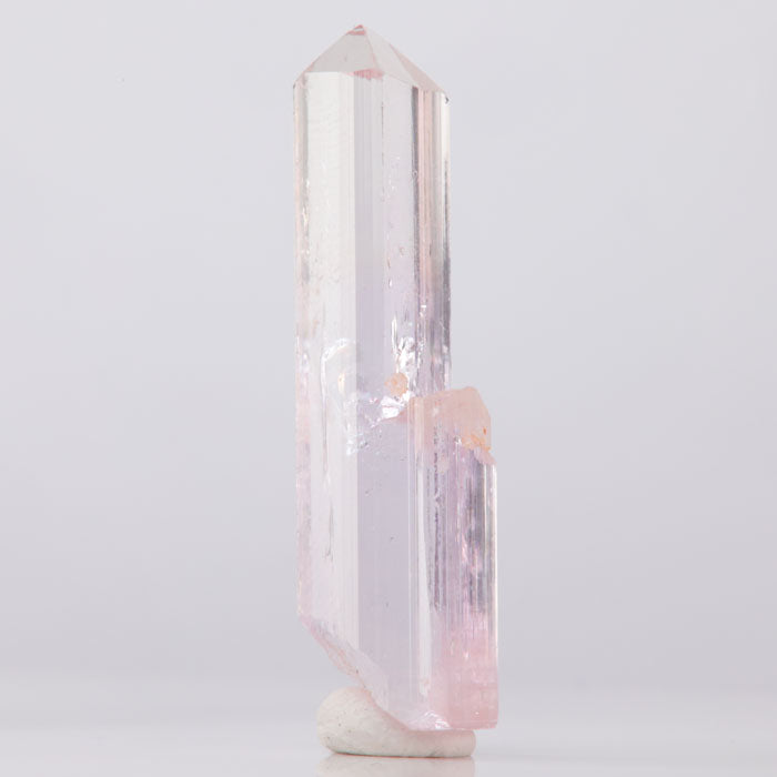 Topaz Crystal tower with pink and white hues on a light gray background