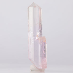 Topaz Crystal tower with pink and white hues on a light gray background