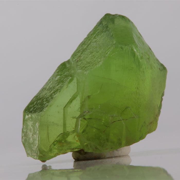 Green crystal on a reflective surface with a gray background