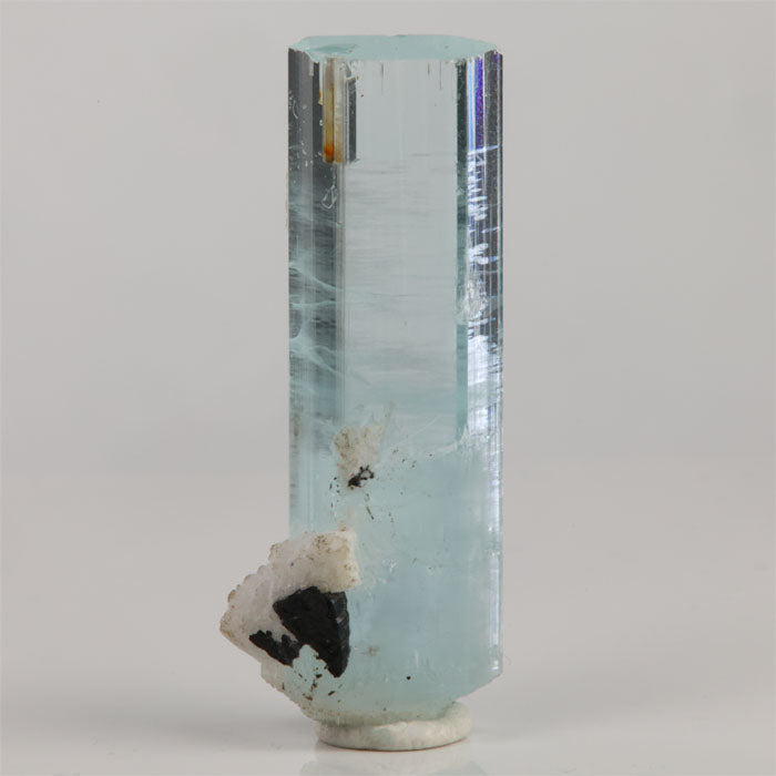 Double-terminated aquamarine crystal from Shigar Mine Pakistan with icy-blue color and black mineral on white matrix.