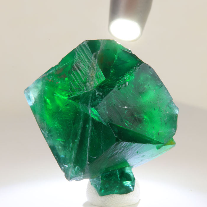 Translucent green Rogerley fluorite specimen illuminated from above, revealing internal clarity, layered growth, and brilliant green color.