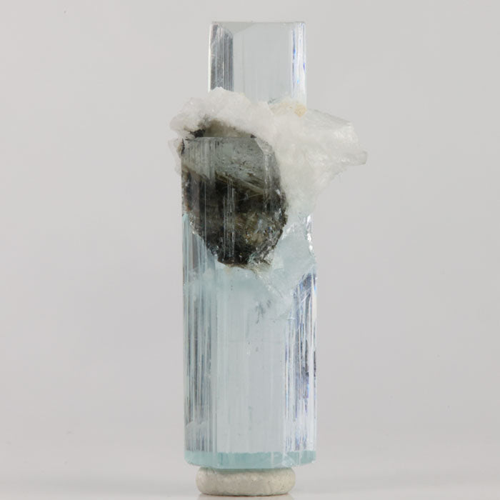 Reverse view of Pakistani aquamarine with fine vertical growth lines and white matrix attached near the center.