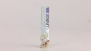 Reverse angle of natural Pakistani aquamarine displaying a narrow hexagonal shape and exceptional transparency along its length.