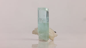 Side view of Pakistani aquamarine revealing internal growth patterns, scattered dark inclusions, and reflective crystal faces.