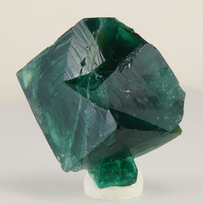 Deep emerald-green Rogerley Mine fluorite twin crystals weighing 47.04 grams, held in hand to show size and natural crystal structure.