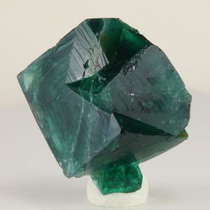 Deep emerald-green Rogerley Mine fluorite twin crystals weighing 47.04 grams, held in hand to show size and natural crystal structure.