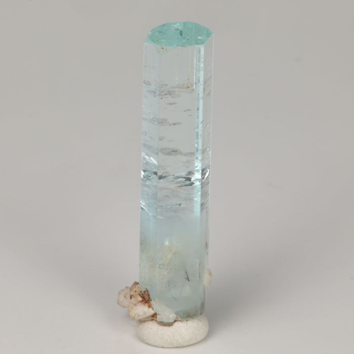 Angled view of aquamarine thumbnail from Skardu Valley showing its natural termination, internal growth features, and light mineral staining.