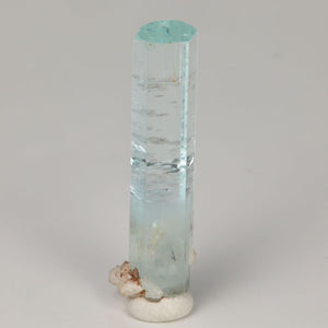 Angled view of aquamarine thumbnail from Skardu Valley showing its natural termination, internal growth features, and light mineral staining.