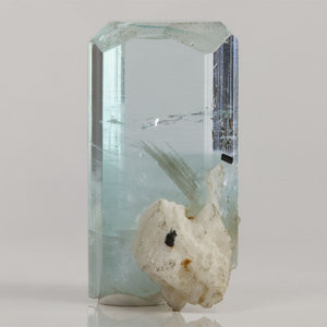 Natural aquamarine thumbnail from Skardu Valley displaying a chunky crystal form with attached white matrix and visible internal details.